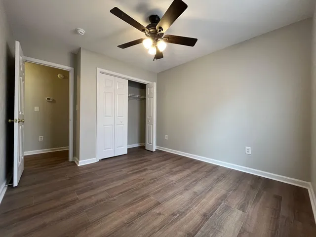 an empty room with wooden floor and a ceiling fan