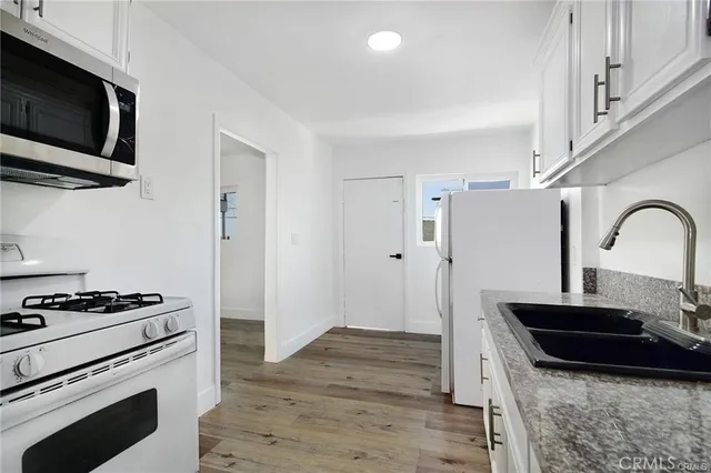 a kitchen with granite countertop cabinets stainless steel appliances and wooden floor