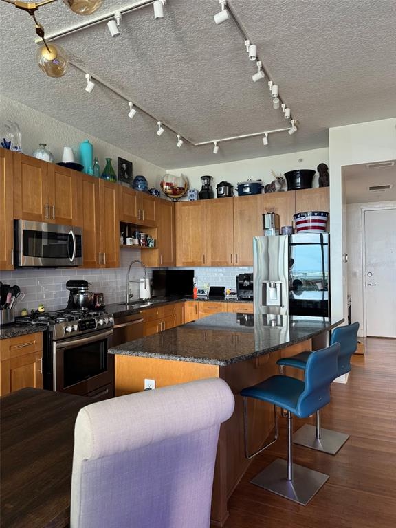 150 East Robinson Street, Unit 2409 Orlando, FL 32801 - Photo 23 of 26 a kitchen with stainless steel appliances granite countertop a stove refrigerator a dining table and chairs with wooden floor
