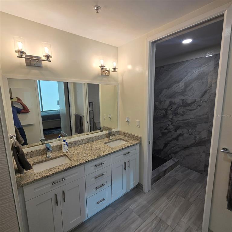 150 East Robinson Street, Unit 2409 Orlando, FL 32801 - Photo 3 of 26 a bathroom with a granite countertop sink a mirror and a shower