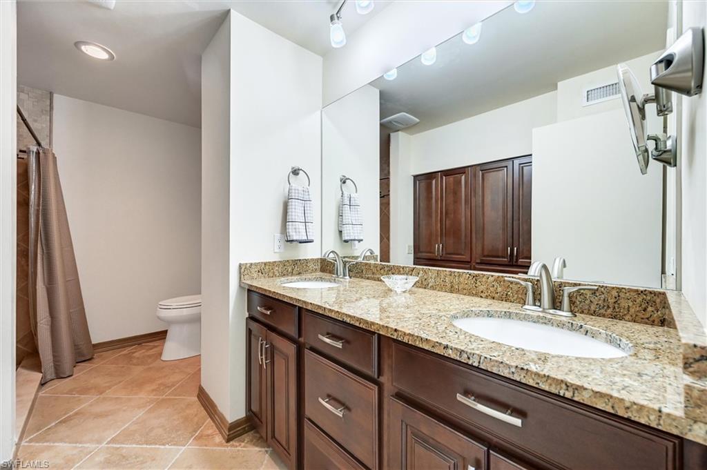185 Lake Point Lane, Unit 8B Naples, FL 34112 - Photo 22 of 34 a bathroom with a granite countertop sink a toilet and a large mirror