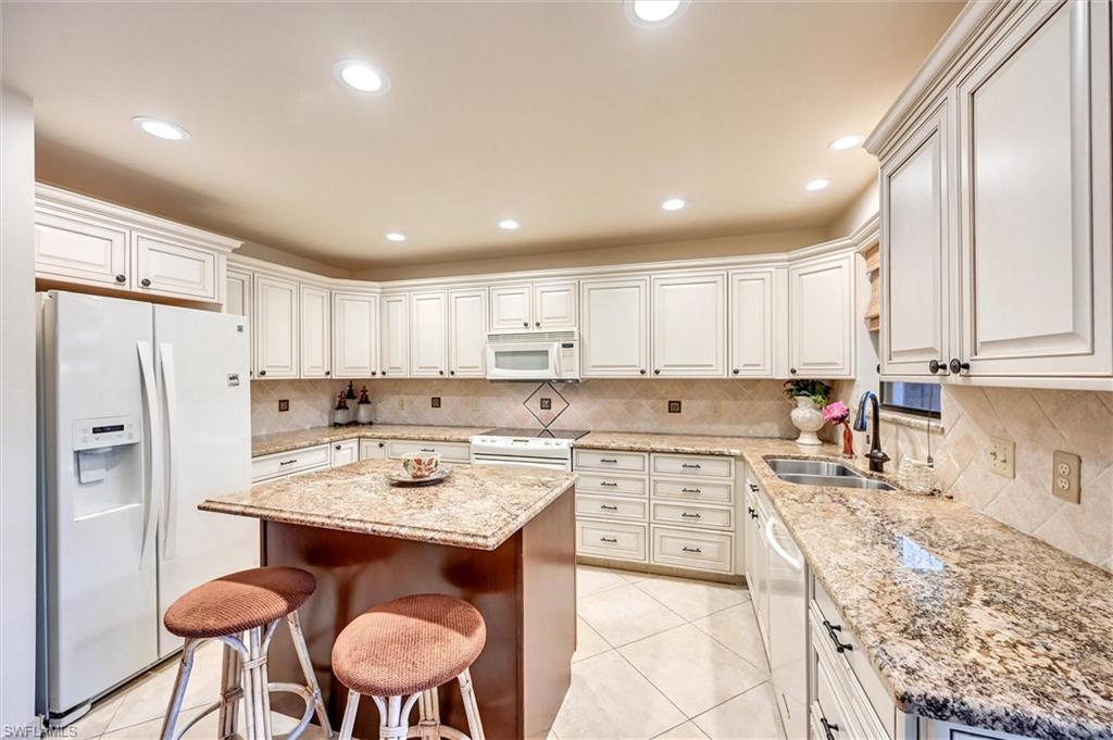 185 Lake Point Lane, Unit 8B Naples, FL 34112 - Photo 4 of 34 a kitchen with stainless steel appliances granite countertop a stove a sink a refrigerator and white cabinets with wooden floor