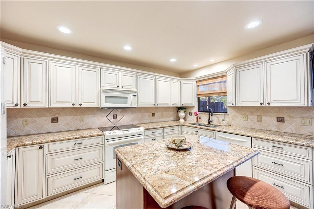 185 Lake Point Lane, Unit 8B Naples, FL 34112 - Photo 5 of 34 a kitchen with granite countertop white cabinets sink and white appliances