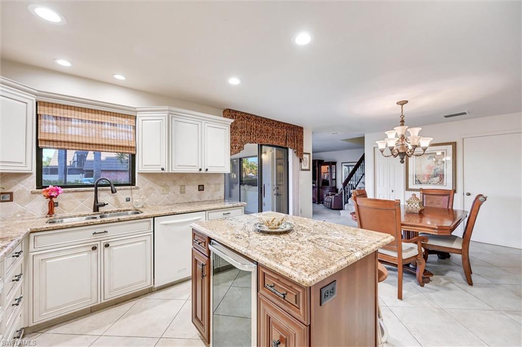 185 Lake Point Lane, Unit 8B Naples, FL 34112 - Photo 6 of 34 a kitchen with a table chairs refrigerator and cabinets