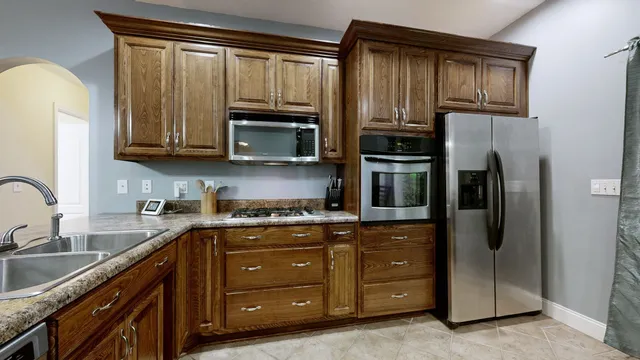 a kitchen with stainless steel appliances granite countertop a refrigerator a stove a sink and cabinets