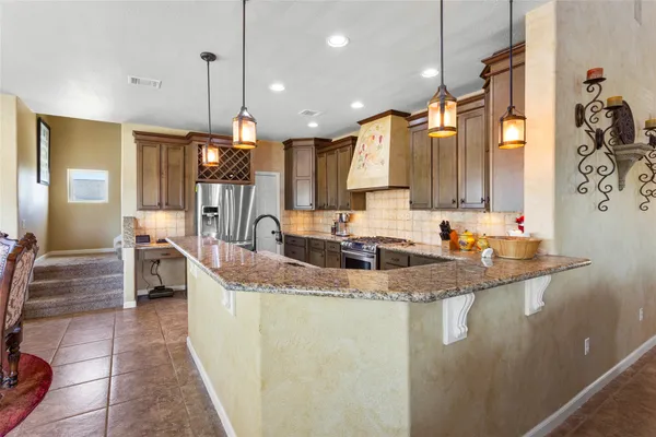 a kitchen with stainless steel appliances granite countertop a stove a sink and a refrigerator