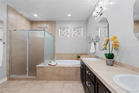 a spacious bathroom with a granite countertop sink a mirror a bathtub and shower