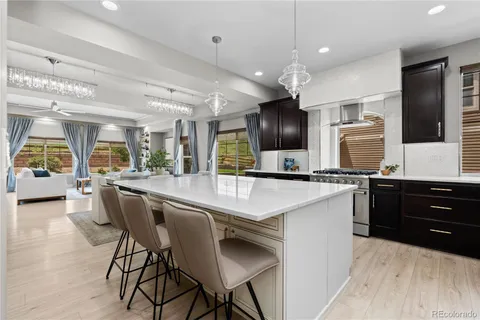 a kitchen with stainless steel appliances kitchen island granite countertop a sink a stove a dining table and chairs