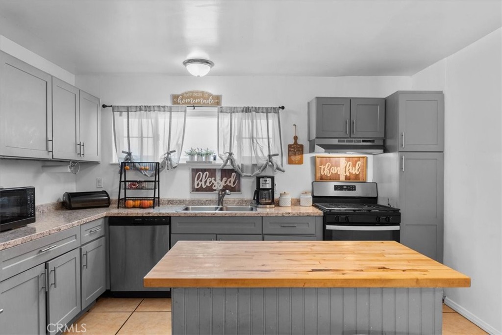 1417 West Marshall Boulevard San Bernardino, CA 92405 - Photo 11 of 39 a kitchen with kitchen island granite countertop a stove top oven a sink a counter space and cabinets