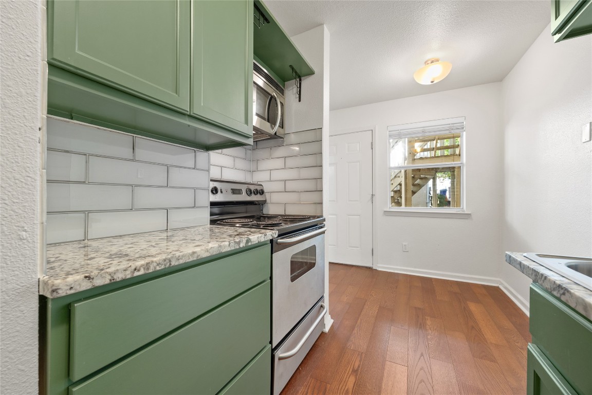 a kitchen with granite countertop cabinets stainless steel appliances and a wooden floor