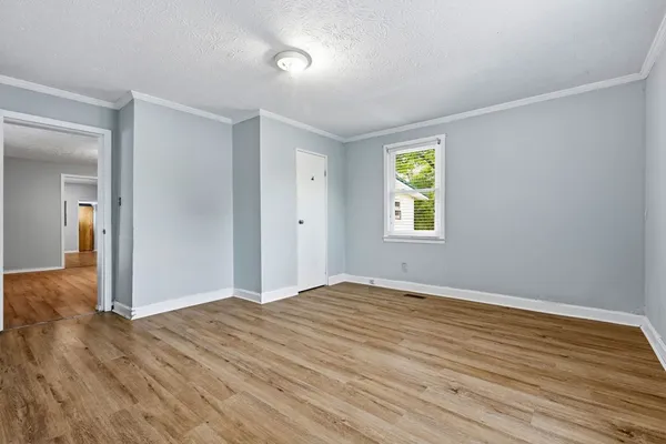 a view of an empty room with wooden floor and window
