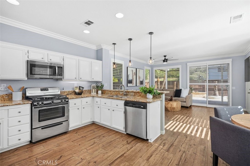 8 Tradition Lane Rancho Santa Margarita, CA 92688 - Photo 5 of 43 a kitchen with stainless steel appliances granite countertop a stove top oven a sink dishwasher a dining table and chairs with wooden floor