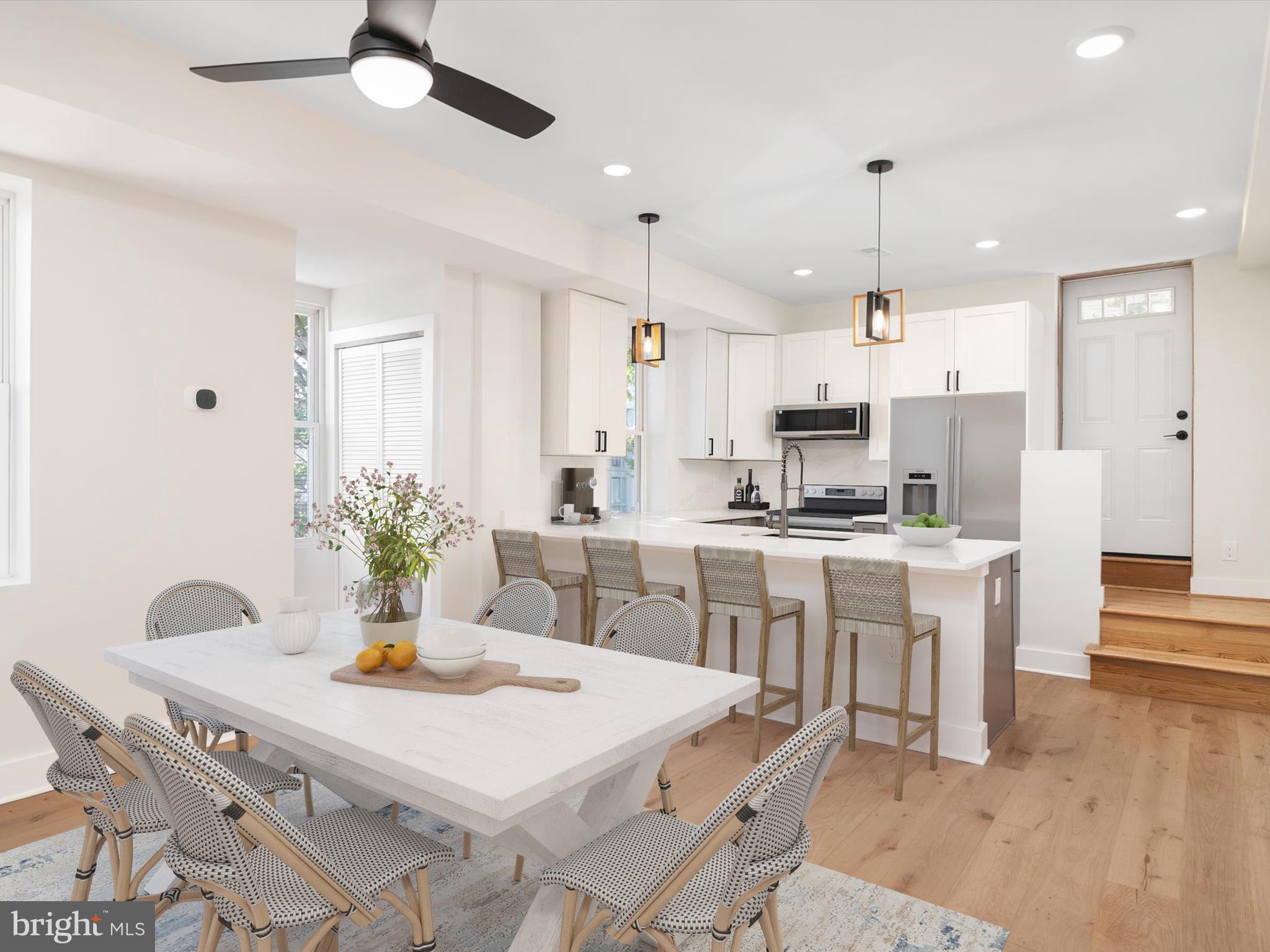 a kitchen with stainless steel appliances kitchen island granite countertop a dining table chairs and white cabinets