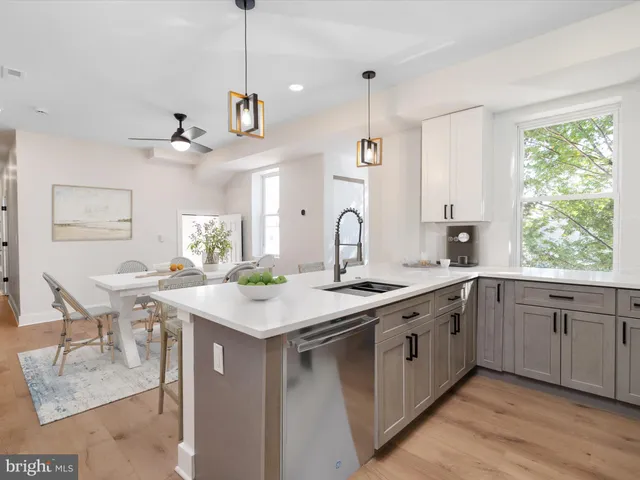 a kitchen with a stove a sink a window and chairs