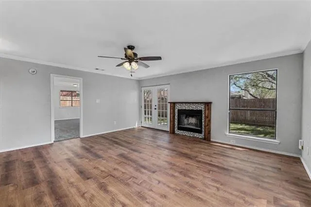 a view of an empty room with wooden floor fireplace and a window