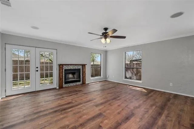 a view of an empty room with wooden floor fireplace and a window