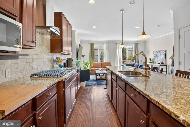 a kitchen with stainless steel appliances granite countertop a stove a sink dishwasher and a microwave with wooden floor