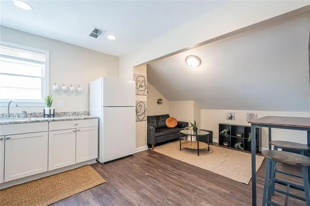 a kitchen with stainless steel appliances granite countertop a refrigerator a stove and a dining table with wooden floor