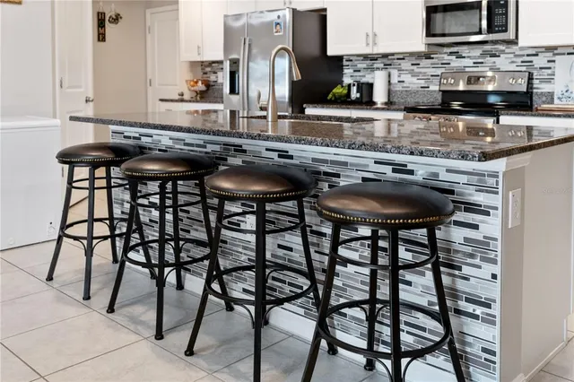 a kitchen with granite countertop a table chairs stove and cabinets