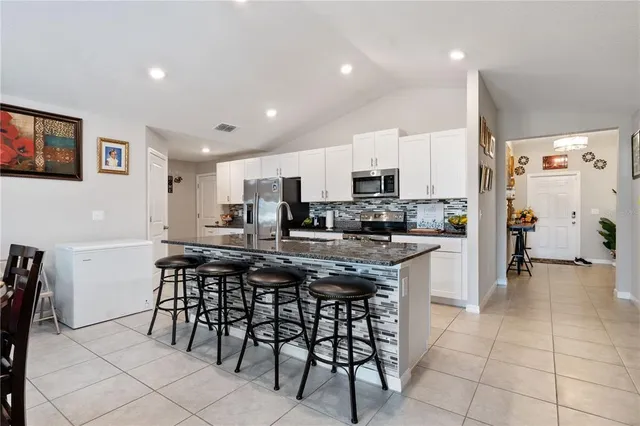 a kitchen with stainless steel appliances a table and chairs in it