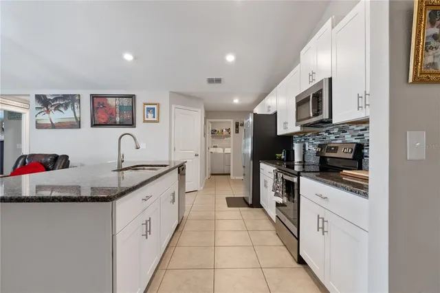 a large kitchen with stainless steel appliances granite countertop a sink and cabinets