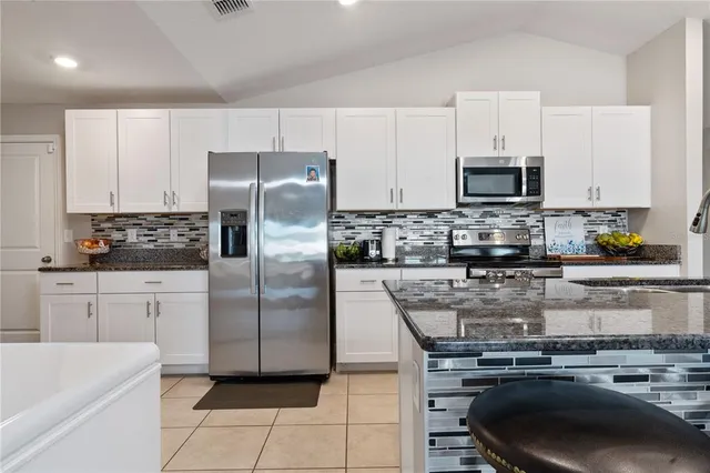 a kitchen with stainless steel appliances granite countertop a sink a stove a microwave and a refrigerator