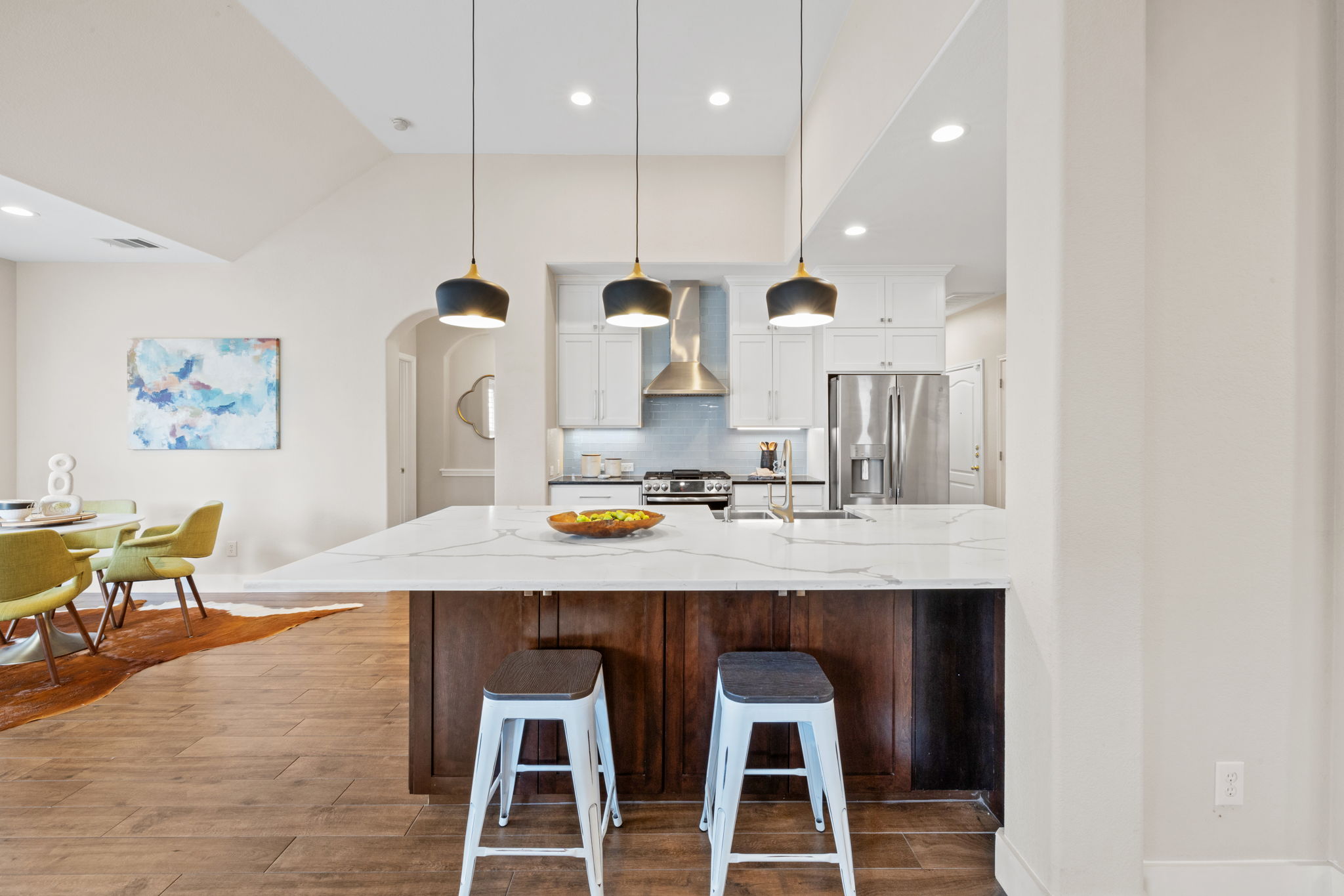 8112 Cobblestone Austin, TX 78735 - Photo 10 of 33 Kitchen featuring appliances with stainless steel finishes, wall chimney range hood, arched walkways, white cabinets, and wood finished floors
