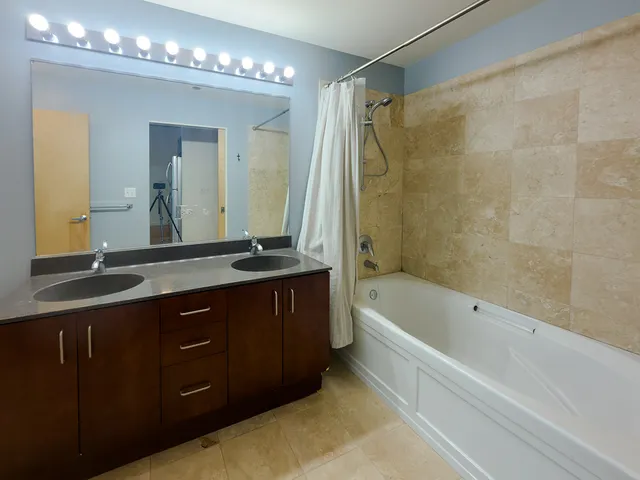a bathroom with a tub a double vanity sink and a mirror