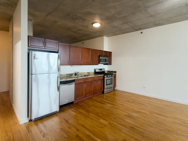 a kitchen with granite countertop a refrigerator and a stove top oven