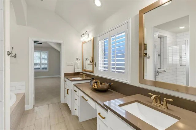 a bathroom with double vanity sinks a granite tub shower and a mirror