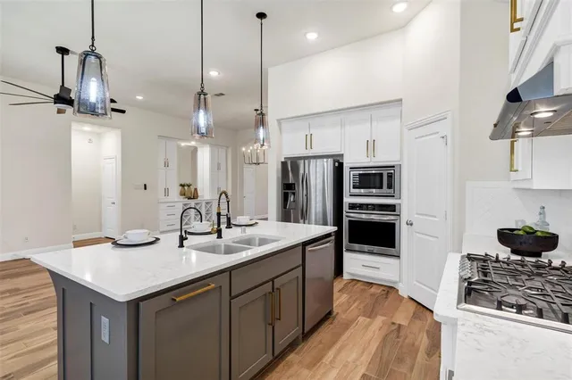 a kitchen with stainless steel appliances a sink a stove a refrigerator and island