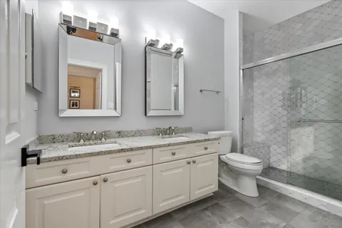 a bathroom with a double vanity sink toilet and a mirror