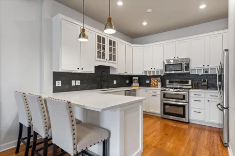 a kitchen with stainless steel appliances kitchen island granite countertop a stove top oven a sink a dining table and chairs