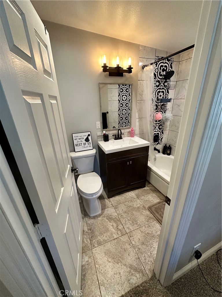 18470 7th Street Bloomington, CA 92316 - Photo 17 of 45 a bathroom with a sink a toilet and shower curtain
