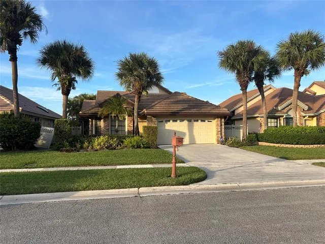 a front view of a house with a yard and palm trees