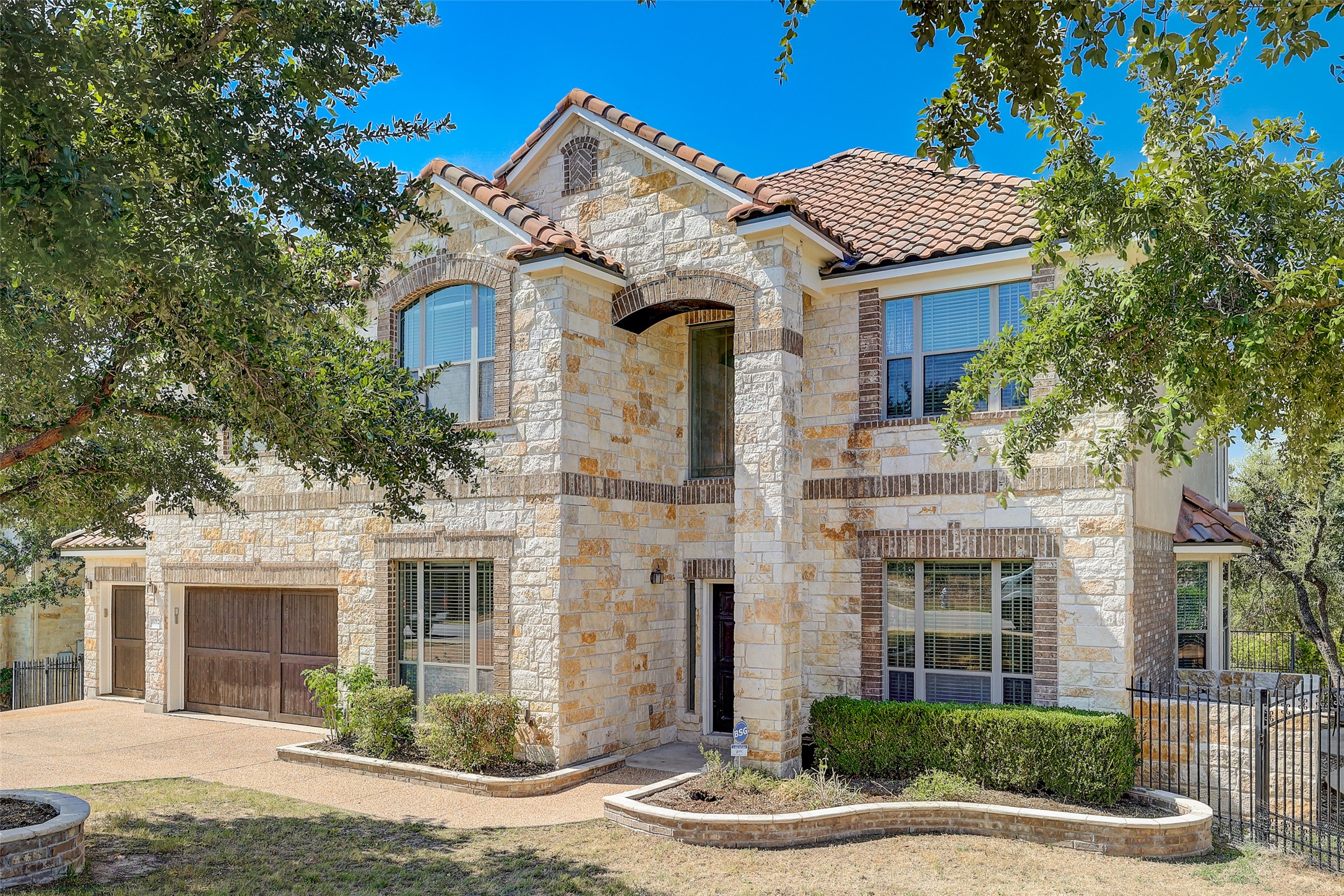 16012 Spillman Ranch Loop Austin, TX 78738 - Photo 5 of 38 This magnificent stone and brick residence presents a distinguished curb appeal with its elegant facade and terracotta roof.