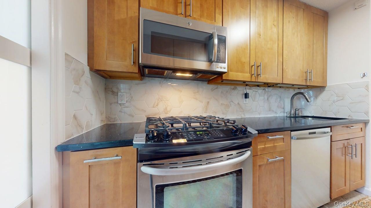 118-17 Union Turnpike, Unit 18H Queens, NY 11375 - Photo 16 of 49 Kitchen with stainless steel appliances, dark stone counters, tasteful backsplash, and brown cabinets