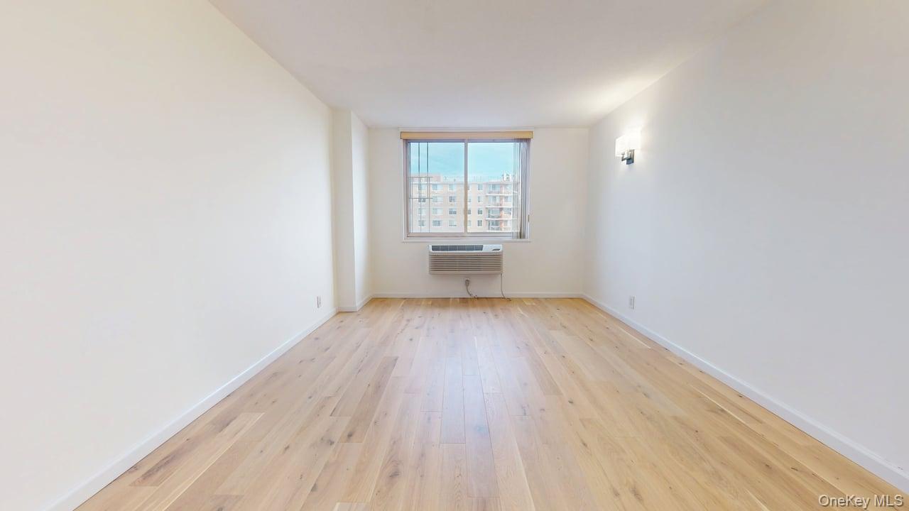 118-17 Union Turnpike, Unit 18H Queens, NY 11375 - Photo 19 of 49 Empty room with light wood-style flooring and an AC wall unit