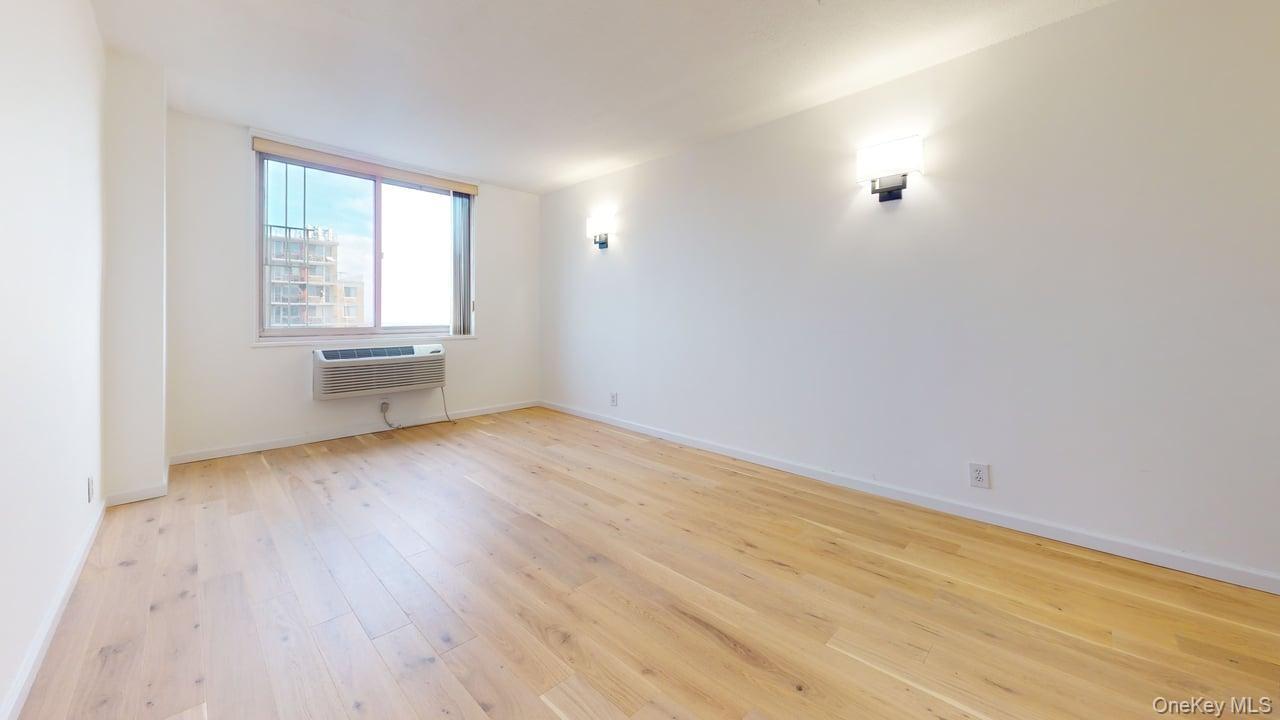 118-17 Union Turnpike, Unit 18H Queens, NY 11375 - Photo 20 of 49 Empty room with light wood finished floors and a wall unit AC