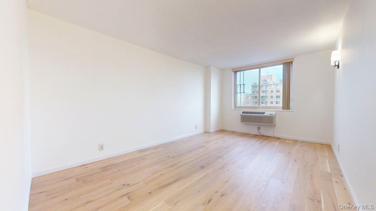 118-17 Union Turnpike, Unit 18H Queens, NY 11375 - Photo 22 of 49 Spare room featuring light wood-style floors and a wall mounted AC