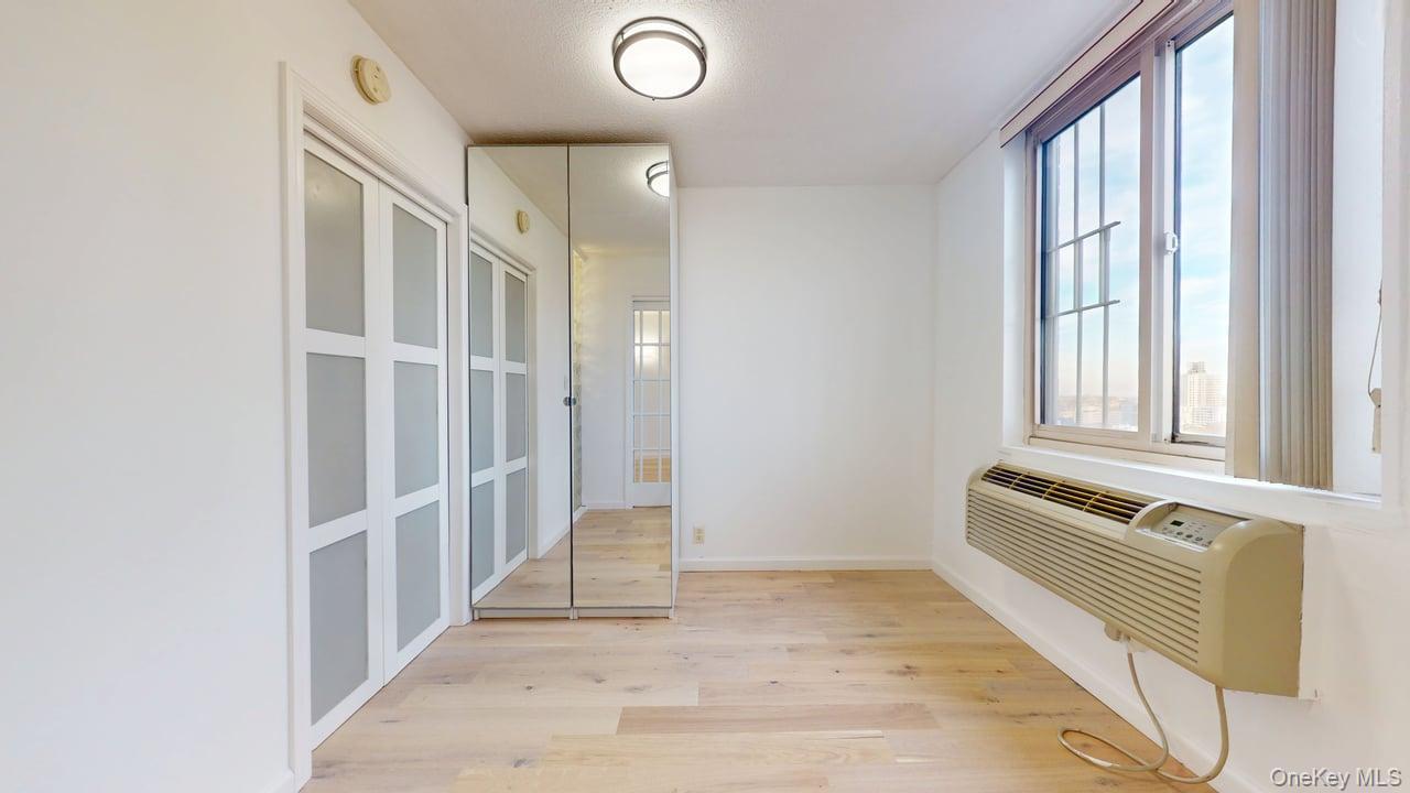 118-17 Union Turnpike, Unit 18H Queens, NY 11375 - Photo 28 of 49 Hall with light wood-style flooring and a wall mounted AC