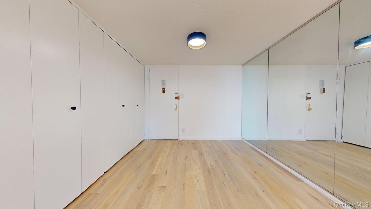 118-17 Union Turnpike, Unit 18H Queens, NY 11375 - Photo 3 of 49 Unfurnished bedroom featuring light wood finished floors and multiple closets