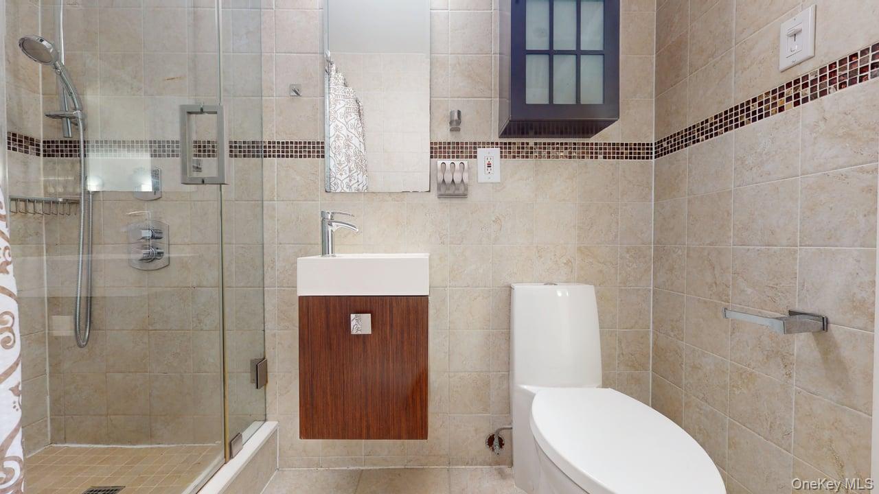 118-17 Union Turnpike, Unit 18H Queens, NY 11375 - Photo 33 of 49 Full bath featuring vanity, a stall shower, and tile walls