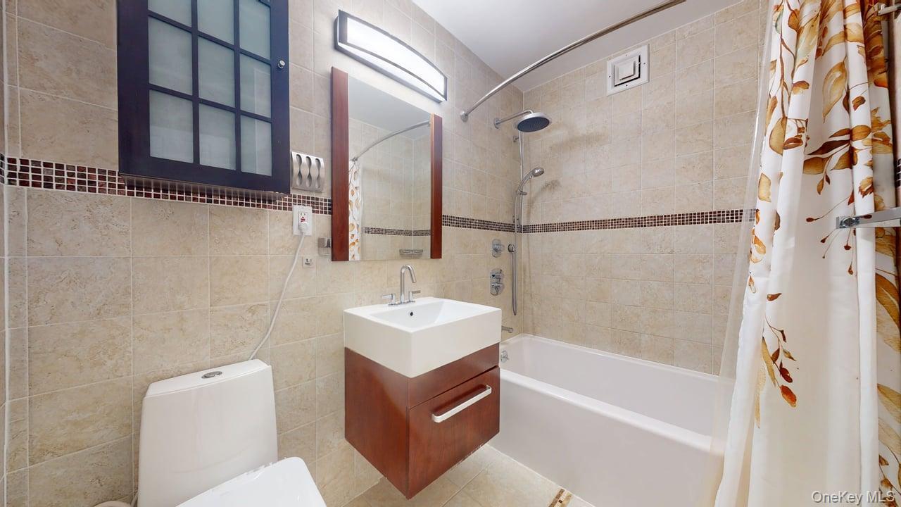 118-17 Union Turnpike, Unit 18H Queens, NY 11375 - Photo 34 of 49 Full bathroom with vanity, tile walls, shower / bathtub combination with curtain, and light tile patterned floors