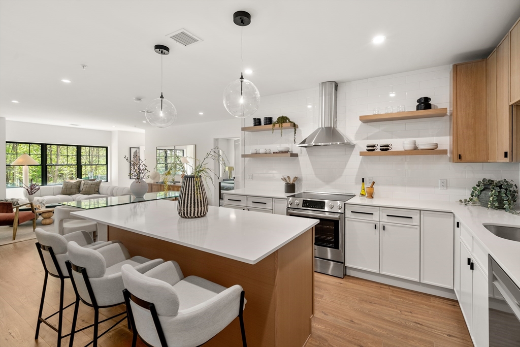 20 Audubon Way, Unit 302 Canton, MA 02021 - Photo 9 of 22 a kitchen with stainless steel appliances granite countertop a stove top oven a sink a refrigerator and white cabinets with wooden floor