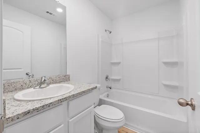 a bathroom with a granite countertop sink a toilet and shower