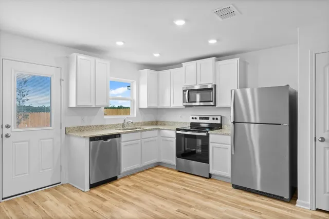 a kitchen with granite countertop a refrigerator stove top oven and sink