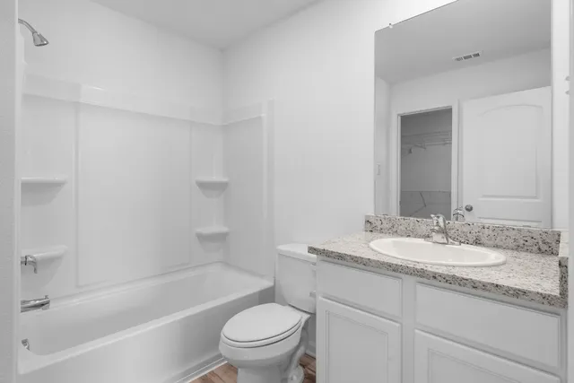 a bathroom with a granite countertop sink a toilet and bathtub