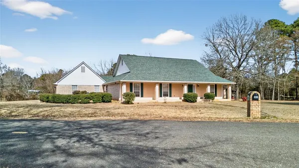 a front view of a house with a dirt yard and a large tree