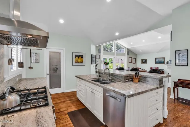 a kitchen with granite countertop a refrigerator stove and white cabinets with wooden floor